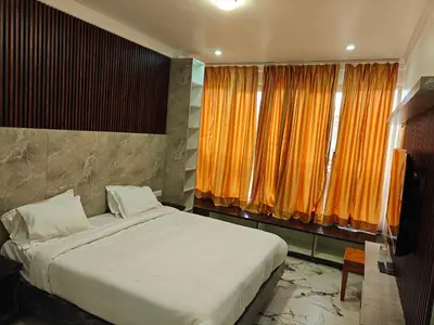 a bedroom with a large bed with orange curtains at The Ooty Suites in Ooty