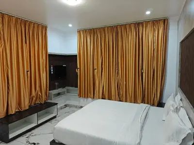 a bedroom with a large bed and curtains at The Ooty Suites in Ooty