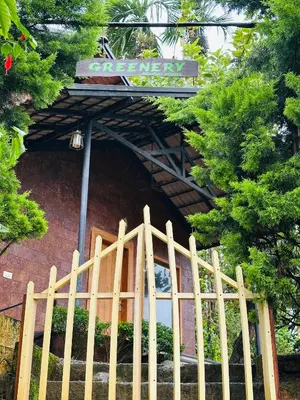 a wooden fence in front of a building with a sign at Greenery Holiday Homes in Meppādi