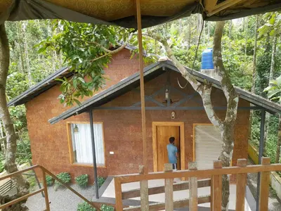 a man standing in the doorway of a brick house at Greenery Holiday Homes in Meppādi
