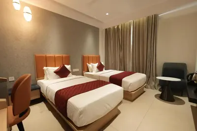 a hotel room with two beds and a table at Hotel Cachet in Coimbatore