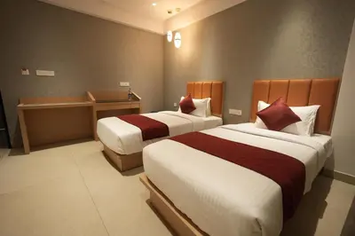 a hotel room with two beds and a desk at Hotel Cachet in Coimbatore