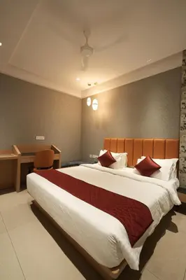 a bedroom with a large bed with red pillows at Hotel Cachet in Coimbatore