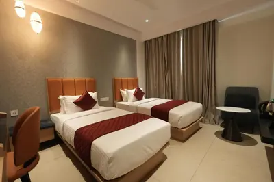 a hotel room with two beds and a table at Hotel Cachet in Coimbatore
