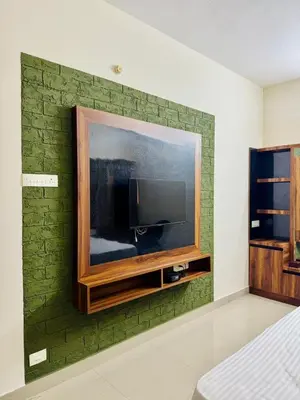 a green brick wall with a flat screen tv on it at Marvee Luxus Stay in Coimbatore