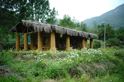 a small hut with a thatched roof in a field at The Misty Mudhouse in Marayoor
