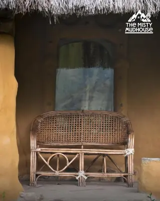 a wicker bench sitting in front of a window at The Misty Mudhouse in Marayoor