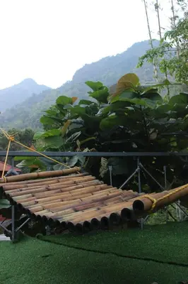 a wooden bench sitting on the grass with mountains in the background at Nilambu Homestay in Nilambūr