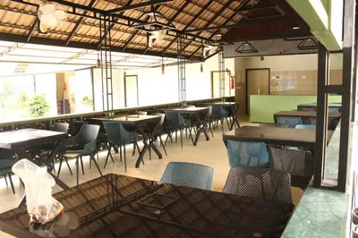 a dining room with tables and chairs in a building at Cozycaza resort in Padinjarathara