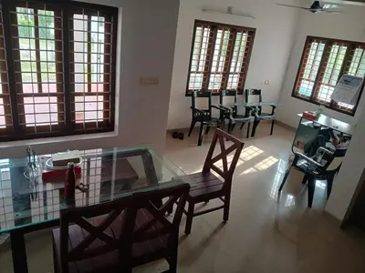 a living room with a glass table and chairs at Staycation Homestay in Ernakulam