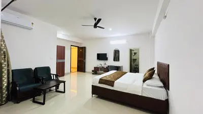 a bedroom with a bed and a chair at Queens Suite Rooms in Channapatna