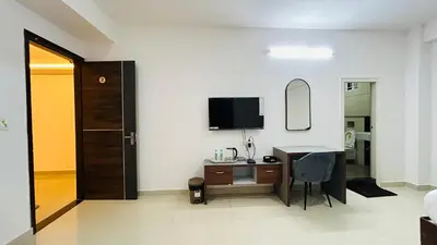 a bedroom with a desk and a tv on a wall at Queens Suite Rooms in Channapatna