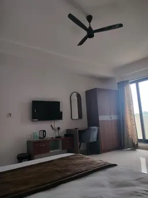 a bedroom with a bed and a ceiling fan at Queens Suite Rooms in Channapatna