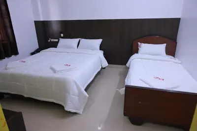 two beds in a hotel room with white sheets at PVR International in Coimbatore