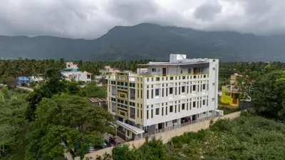 a large white building with a mountain in the background at Sree Bharat Apartment in Coimbatore