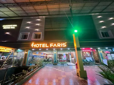 a hotel with a neon sign in front of a building at FARIS ROOMs in Malappuram