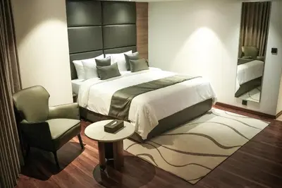 a bedroom with a large bed and a chair at Oshin Calicut in Kozhikode