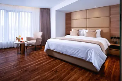 a hotel room with a large bed and a chair at Oshin Calicut in Kozhikode