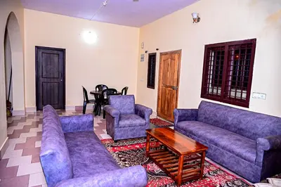 a living room with purple couches and a table at Coorg mansion in Madikeri