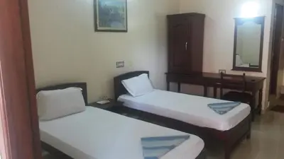 a room with two beds and a desk and a mirror at Mahe Residency in Mahe