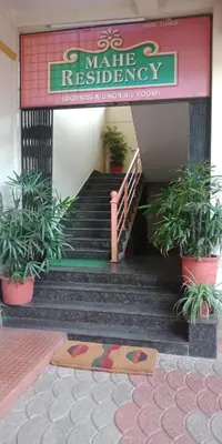 a restaurant with stairs and potted plants in front of it at Mahe Residency in Mahe