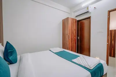 a bedroom with a white bed and a wooden cabinet at D Nest Inn in Trichūr
