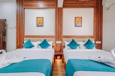 two beds in a room with blue and white at D Nest Inn in Trichūr