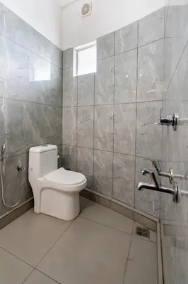 a bathroom with a toilet and a tiled wall at D Nest Inn in Trichūr