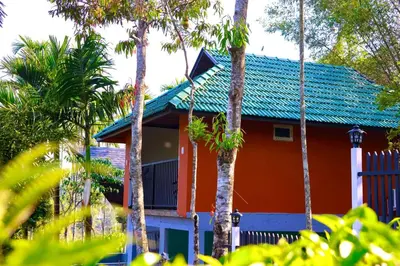 a house with a blue roof and palm trees at Hayashi Resort in Meppādi