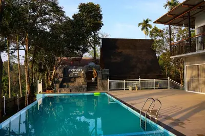 a swimming pool in front of a house at Hayashi Resort in Meppādi