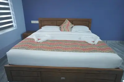a bedroom with a large bed with a wooden headboard at Hamai Grand Home Stay Rooms Wayanad in Ambalavayal