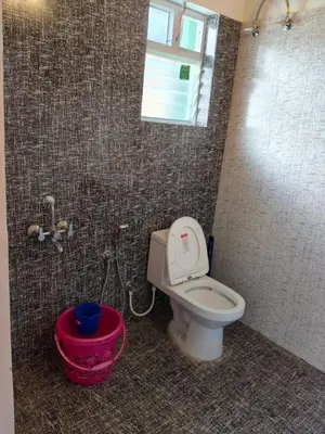 a bathroom with a white toilet and a shower at Westhill Daffodils Inn - II Ooty in Ooty