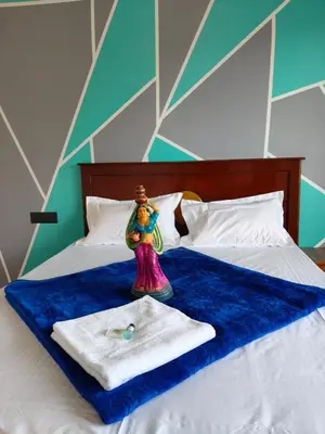 a doll sitting on top of a bed with a towel at Westhill Daffodils Inn - II Ooty in Ooty
