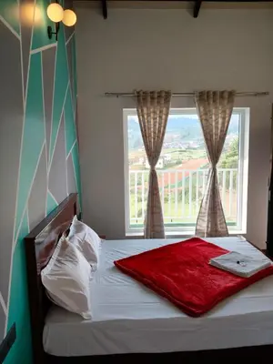 a bed with a red blanket and a window at Westhill Daffodils Inn - II Ooty in Ooty