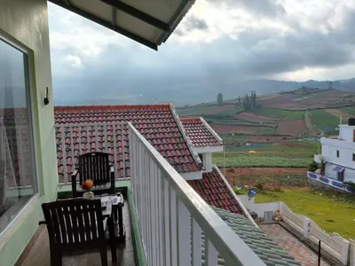 a balcony with two chairs and a view of a house at Westhill Daffodils Inn - II Ooty in Ooty