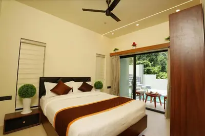 a bedroom with a large bed and a balcony at LA VILLA VYTHIRI Resort in Vythiri