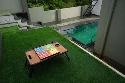 a table sitting on the grass next to a swimming pool at LA VILLA VYTHIRI Resort in Vythiri