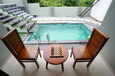 a view of a pool with two chairs and a chessboard at LA VILLA VYTHIRI Resort in Vythiri