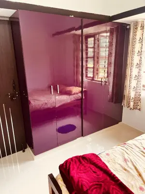 a bedroom with a purple cabinet with two beds at Kannada Maathe Home Stay- Golden Temple-Tibet camp 2 km far in Kushālnagar