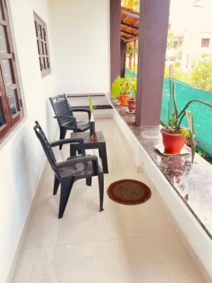 a balcony with two chairs and a table on a porch at Kannada Maathe Home Stay- Golden Temple-Tibet camp 2 km far in Kushālnagar