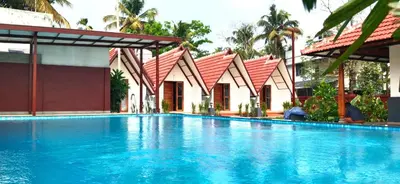 a large blue swimming pool next to a building at Dhruv Heritage Lake Resort Cherai in Cochin