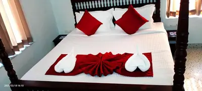 a bedroom with a bed with red pillows and shoes at Dhruv Heritage Lake Resort Cherai in Cochin