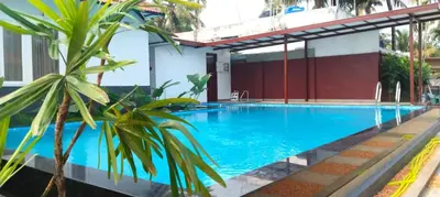 a large swimming pool with a palm tree in front of a building at Dhruv Heritage Lake Resort Cherai in Cochin