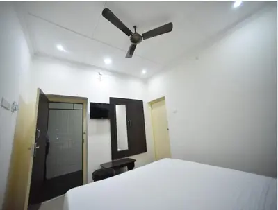 a bedroom with a white bed and a ceiling fan at PRM Aruna Lodge in Erode