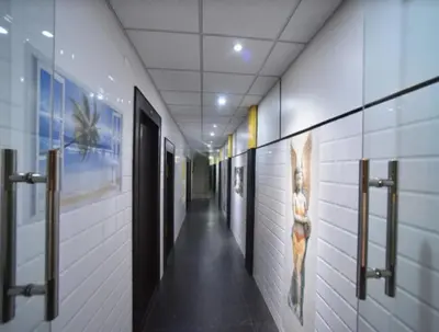 a hallway in a building with doors and paintings on the walls at PRM Aruna Lodge in Erode