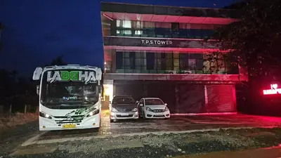 a bus and two cars parked in front of a building at J TEN Residency in Meenangadi