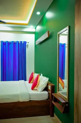 a bedroom with a bed with a mirror and blue curtains at J TEN Residency in Meenangadi