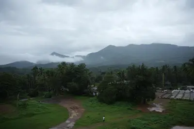 a person standing in a field with mountains in the background at Denz Paradise in Kelakam