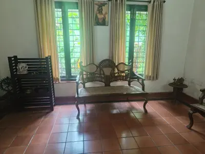 a living room with chairs and windows and a tiled floor at Utthara Tharavadu in Irinjālakuda