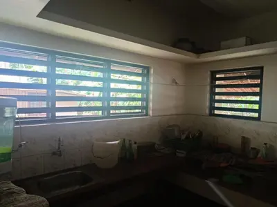 a kitchen with a sink and two windows in it at Utthara Tharavadu in Irinjālakuda